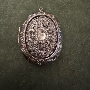 Locket, crystals on front. Opens to store something small or a picture. Silver